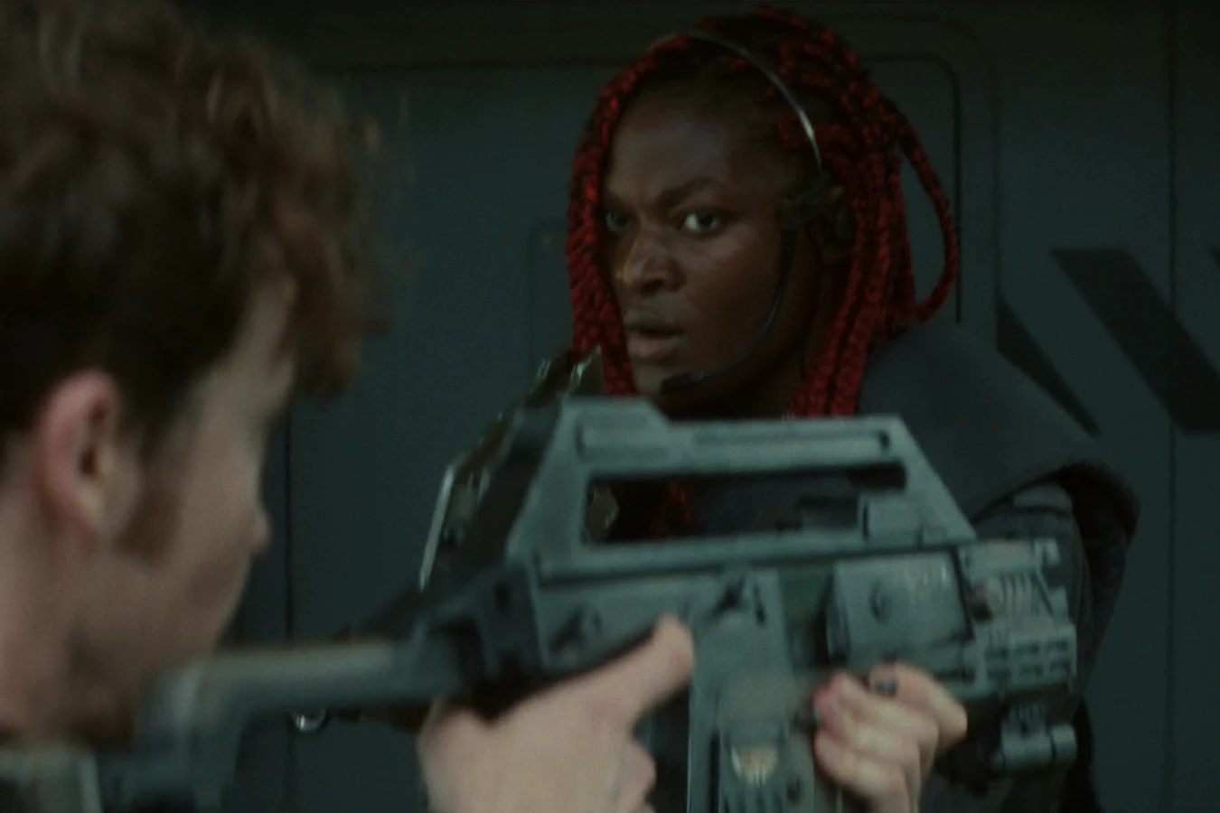 Siberian aiming her pulse rifle behind Joe Hermit during the standoff at the Neverland boat dock in Alien: Earth