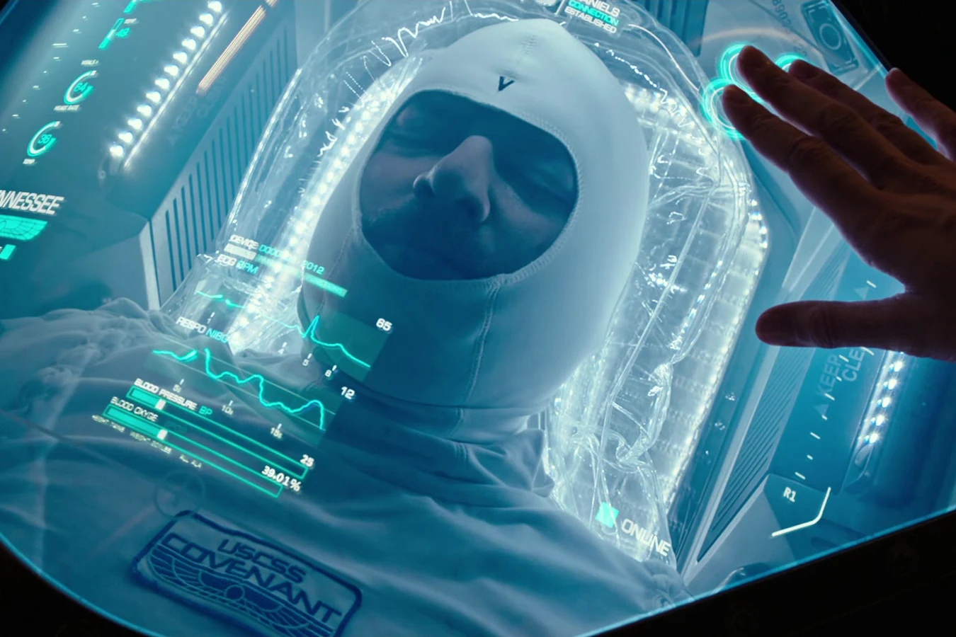 A Covenant hypersleep pod with a sleeper under the glass and a hand resting on the lid