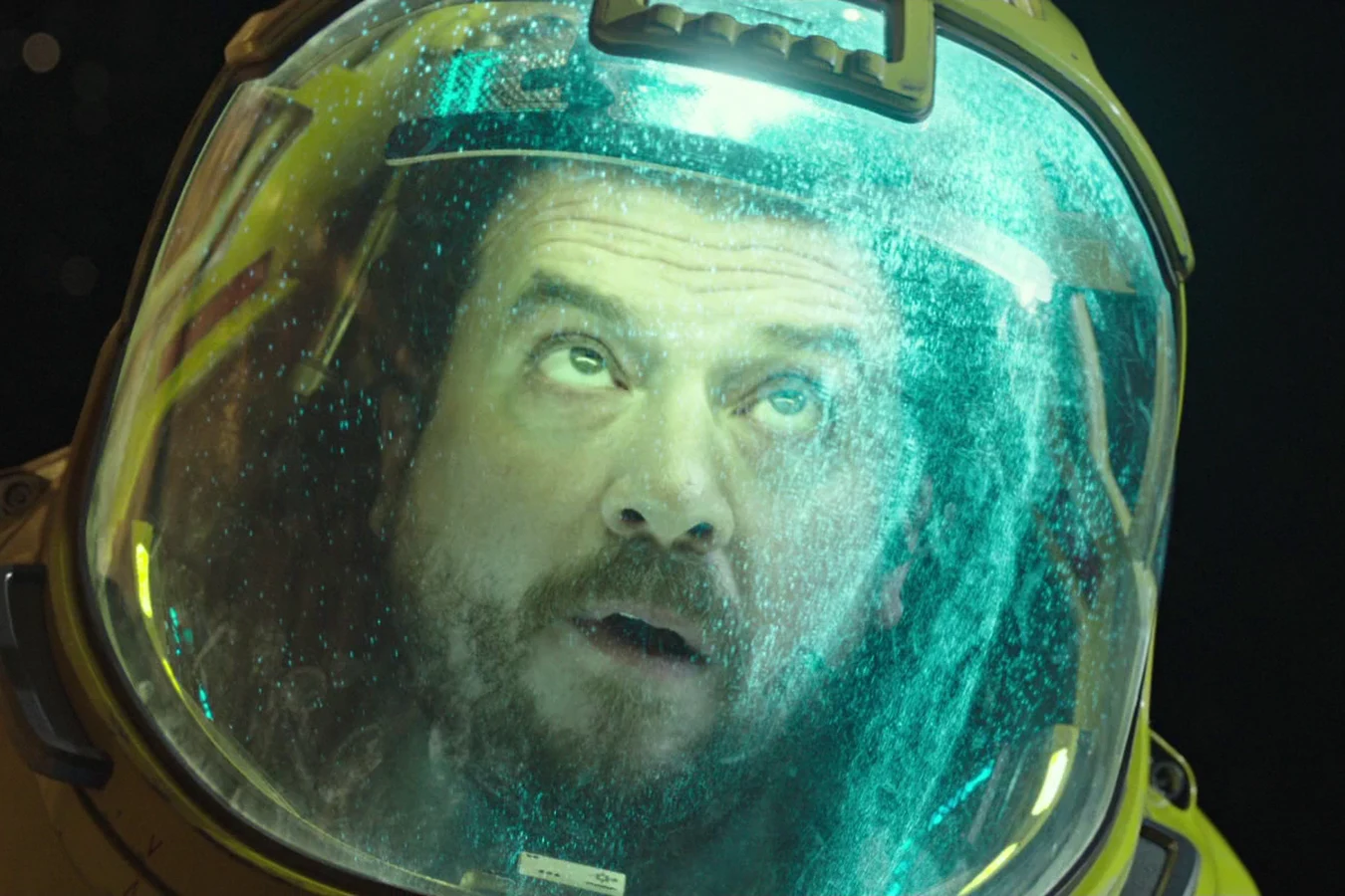 Tennessee in a yellow EVA suit looking up through a fogged visor