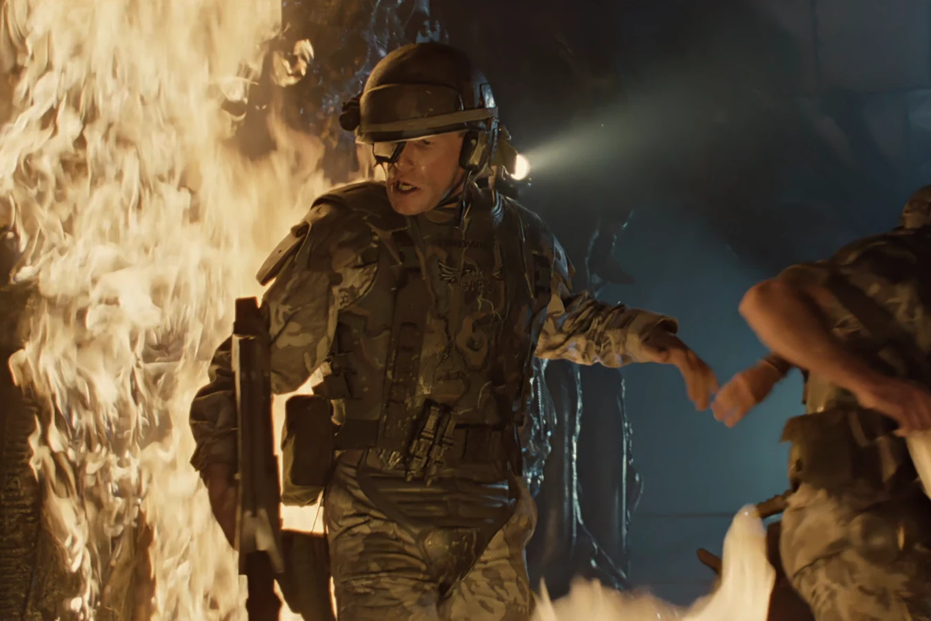 Private Crowe holding an M41A Pulse Rifle in the Hadley's Hope hive as flame lights the corridor