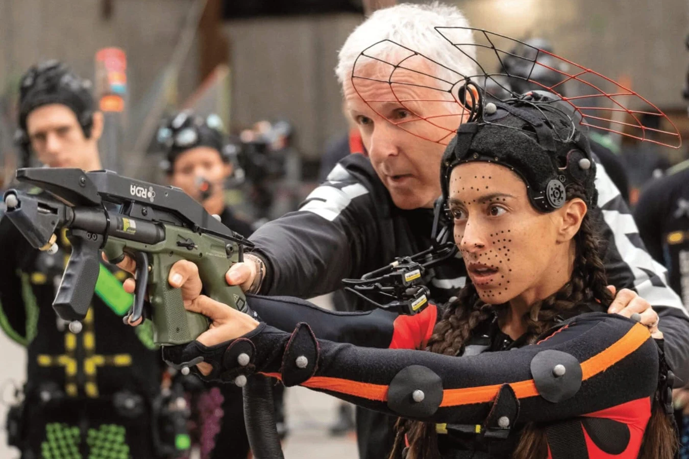 James Cameron coaching Oona Chaplin in a marker suit as she aims an RDA rifle on the Avatar volume
