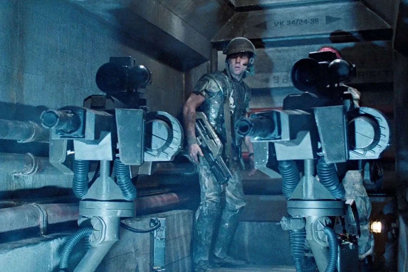 Hudson standing between UA 571-C sentry guns in a Hadley's Hope corridor in Aliens