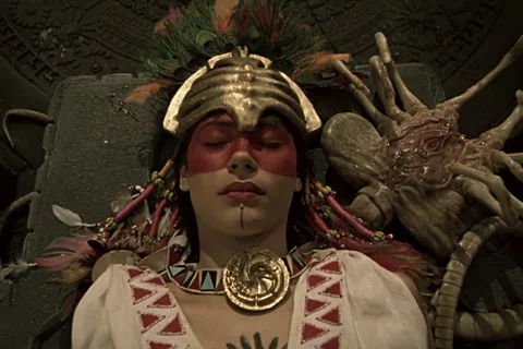 A ceremonial sacrificial woman lying beside a Facehugger