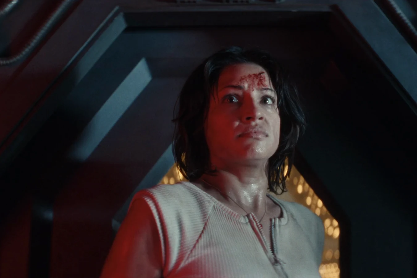 Bloodied Zoya Zaveri looking up at the sealed Mother chamber door in red emergency light in Alien: Earth